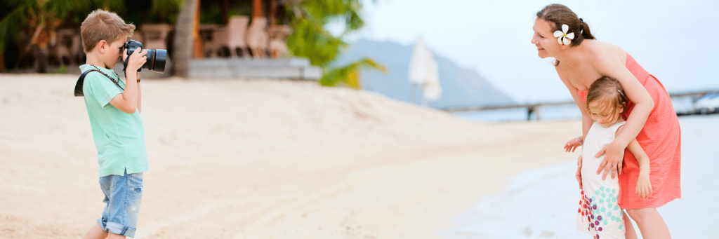 A boy taking a picture of a woman and a girl with a camera